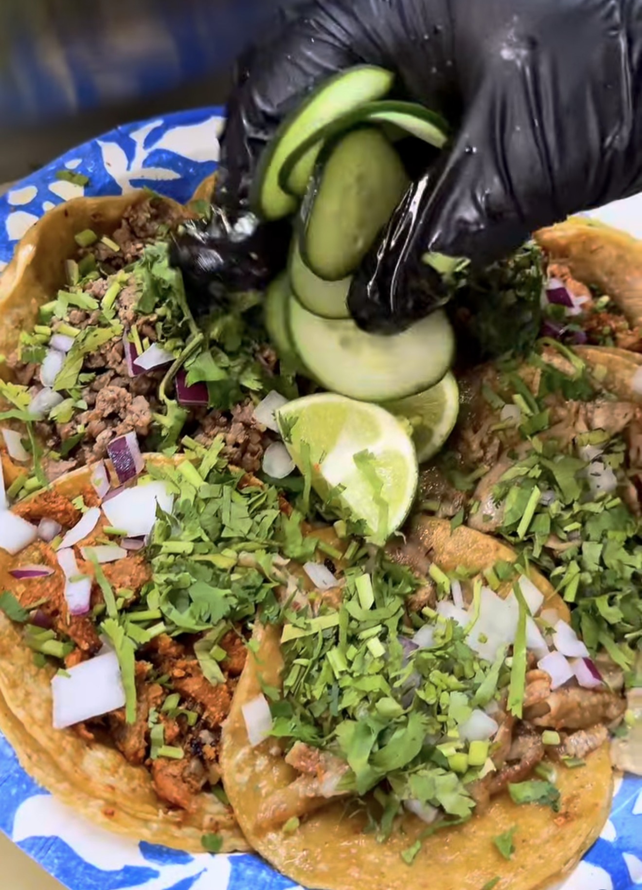 Six street tacos topped with cilantro, onion, cucumber and lime