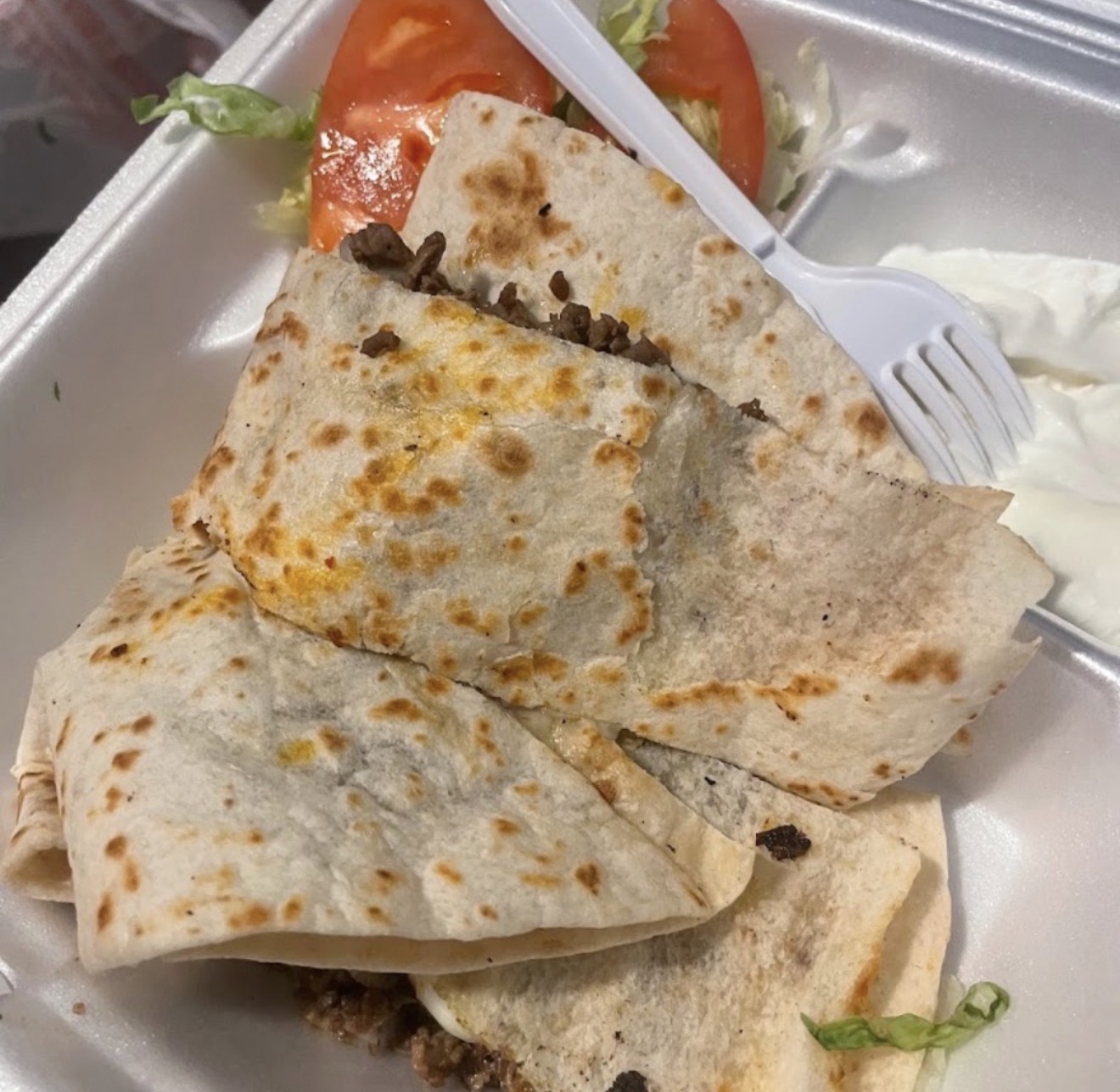 Al pastor quesadilla with lettuce, tomato and crema in a to-go tray